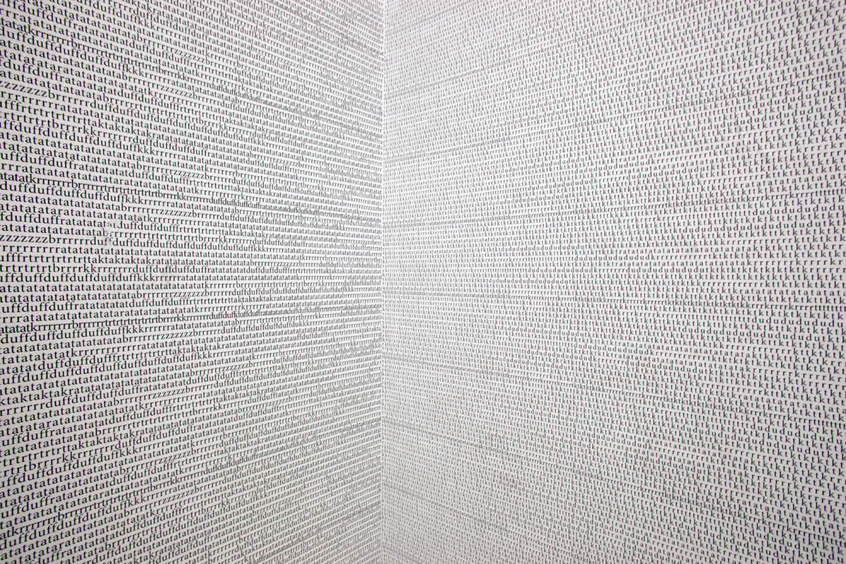Detail of a corner of the room. From the left and right, the small lines of letters run in perspective toward the corner. The letters at the edges of the image are sharp, for example, you can read "zzzzduffduffrrrratatata". The line spacing is slightly smaller than usual for a text, the mass of letters almost flickers.